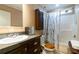 Well-lit bathroom with a dark wood cabinet, updated sink, and combined tub and shower with patterned curtain at 7024 Evergreen Way, Buford, GA 30518