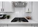 Close-up of a modern kitchen featuring a gas cooktop, white cabinets, and stainless steel range hood at 8The07 Stickley Oak Way, Woodstock, GA 30189