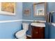 Charming half bathroom featuring blue walls, framed mirror, and pedestal sink with cherry wood vanity at 2296 Raven Cir, Lithonia, GA 30058