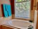 Bright bathroom featuring a large soaking tub beneath a window with tile surround and decorative accents at 6972 Sandtown Ln, Stone Mountain, GA 30087