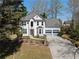 Charming two-story home features a well-manicured lawn, grey garage doors and a red front door at 6972 Sandtown Ln, Stone Mountain, GA 30087