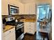 White kitchen that leads to breakfast area featuring stainless steel appliances, stone countertops and backsplash at 6972 Sandtown Ln, Stone Mountain, GA 30087