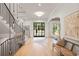 Bright foyer with wooden floors, stairway with hanging lights, and black framed glass front door at 1074 Moores Mill Nw Rd, Atlanta, GA 30327