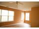 Bedroom featuring a tray ceiling with a ceiling fan, two windows with white blinds, and light orange colored walls at 1972 Ashwood Grove Dr, Snellville, GA 30078