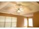 Bedroom featuring a tray ceiling with a ceiling fan, two windows with white blinds, and light orange colored walls at 1972 Ashwood Grove Dr, Snellville, GA 30078