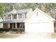 Charming two-story home with light yellow siding, brick accents, and an attached two-car garage, surrounded by lush greenery at 1972 Ashwood Grove Dr, Snellville, GA 30078