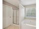 Bathroom featuring walk-in shower, soaking tub, a window, and neutral paint at 3936 Toccoa Falls Dr, Duluth, GA 30097