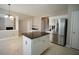 Open-concept kitchen featuring a stainless steel refrigerator, center island with granite countertop, and tile flooring at 3936 Toccoa Falls Dr, Duluth, GA 30097