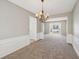 Living room featuring wainscoting detail, chandelier, neutral carpet, and a large window at 3936 Toccoa Falls Dr, Duluth, GA 30097