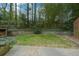 A backyard with a grass lawn, a stone retaining wall, and lush greenery surrounded by trees at 1245 Briar Hills Ne Dr, Atlanta, GA 30306