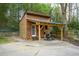 A backyard outbuilding with a covered area, adjacent to a concrete pad and surrounded by trees at 1245 Briar Hills Ne Dr, Atlanta, GA 30306