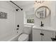 Bright bathroom features white tile, dark fixtures, updated vanity, and round decorative mirror at 2870 Ridgemore Nw Rd, Atlanta, GA 30318