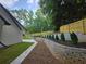 Well-maintained backyard features a stone retaining wall, lush lawn, mature trees, and a charming wooden fence at 1960 Calvin Dr, Duluth, GA 30097