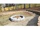 A backyard firepit made of light stones is surrounded by a border of dark bricks and tan stones at 1960 Calvin Dr, Duluth, GA 30097