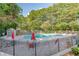Community pool featuring red umbrellas, mature trees and greenery surrounding the fence at 3987 Bayside Cir, Atlanta, GA 30340
