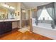 Well-lit bathroom featuring a glass shower, soaking tub, and vanity at 7514 Absinth Dr Pass, Atlanta, GA 30349
