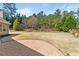 Large backyard with a stone patio, lush green grass, and tall trees at 79 Tiffany Trce, Palmetto, GA 30268