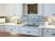White countertops with light mosaic backsplash, modern fixtures, and white cabinets create an elegant kitchen space at 3230 Munsey Ct, Cumming, GA 30041