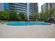 Large, luxurious community pool surrounded by trees, lounge chairs, and modern buildings at 44 Peachtree Nw Pl # 629, Atlanta, GA 30309
