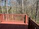 This wooden deck has a red-painted railing with a view of wooded backyard at 120 Grove Ln, Temple, GA 30179
