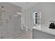 Bright bathroom featuring a glass shower, modern fixtures, and a gray vanity under a sunny window at 345 Sugarview Rd, Sugar Hill, GA 30518