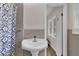 Bathroom features a pedestal sink, neutral tiling, and a shower with blue patterned curtain at 3441 Palace Ct, Tucker, GA 30084