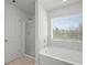 Bathroom featuring a tub, glass enclosed shower, and large window at 7083 Gladstone Cir, Stonecrest, GA 30038