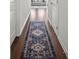 Hallway featuring hardwood floors, a patterned blue runner, and bright white walls at 7083 Gladstone Cir, Stonecrest, GA 30038