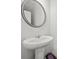 Simple powder room with a pedestal sink and round mirror at 7083 Gladstone Cir, Stonecrest, GA 30038