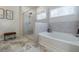 Bright bathroom featuring a glass shower, a soaking tub, gray tile flooring, and modern fixtures at 4870 Odum View Ln, Cumming, GA 30040