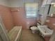 Small pink-tiled bathroom featuring a bathtub, toilet, and vanity at 103 Woodhaven Dr, Stockbridge, GA 30281