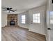 Bright living room featuring a stone fireplace, ceiling fan, wood-look flooring, and a white paneled front door at 4805 Kellys Mill Nw Dr, Lilburn, GA 30047