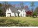 A charming two-story home with a well-manicured lawn, a tree with red leaves and white brick at 966 Laurel Springs Sw Ln, Marietta, GA 30064