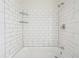 Bathroom shower featuring a white tiled wall with glass shelves, a showerhead, and modern fixtures at 2391 Cove Rd, Lithonia, GA 30058