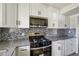 Modern kitchen features white cabinets, stainless steel appliances, granite countertops, and decorative backsplash at 2391 Cove Rd, Lithonia, GA 30058