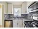 Bright kitchen featuring stainless steel appliances, granite countertops, white cabinetry, and a stainless sink at 2391 Cove Rd, Lithonia, GA 30058