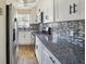 Well-lit kitchen featuring stainless steel appliances, granite countertops, white cabinetry and tile backsplash at 2391 Cove Rd, Lithonia, GA 30058