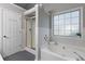 Bathroom showcasing a soaking tub beneath a window, a glass-enclosed shower, and tile accents at 2650 Hamilton Chase Run, Buford, GA 30519