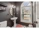 Modern half bathroom with a pedestal sink, decorative mirror, and unique black and white flooring at 1085 Grace Hadaway Ln, Lawrenceville, GA 30043