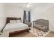 Bright bedroom featuring a wooden bed frame, gray armchair, and matching crib with a stylish geometric rug at 1085 Grace Hadaway Ln, Lawrenceville, GA 30043