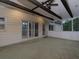 Covered outdoor patio with wooden beams, ceiling fan, herringbone tile flooring, and exterior door at 1514 Haven Crest Dr, Powder Springs, GA 30127