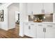 Kitchen with white cabinetry, quartz countertops, and stylish backsplash that complements the hardwood flooring at 2550 Bertrand Way, Cumming, GA 30041