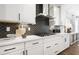 Modern kitchen features white cabinets, stainless steel appliances, and unique backsplash design at 2550 Bertrand Way, Cumming, GA 30041