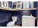 Stylish powder room with dark blue walls, floating wood shelf, and modern white sink at 1168 Mado Loop, Chattahoochee Hills, GA 30268