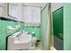 Retro bathroom with green tiles, black accents, a vintage sink, and patterned tile floor at 1420 Elizabeth Ln, East Point, GA 30344