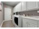 Spacious laundry room features white cabinetry, tile flooring, sink and modern appliances at 7090 Blue Sky Drive, Locust Grove, GA 30248