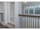 Upstairs hallway with dark metal railing, plush carpet, and views of the surrounding woods at 8245 Dawson View Way, Cumming, GA 30028