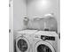 Well-equipped laundry room featuring a modern, white washer and dryer set with storage shelving above at 1115 Martin Luther King Jr Sw Dr, Atlanta, GA 30314