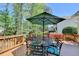 Inviting outdoor deck with a table and chairs under an umbrella, surrounded by lush greenery and trees at 865 Mount Katahdin Trl, Johns Creek, GA 30022