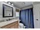 Bathroom with a granite vanity, a large mirror, a shower with a blue curtain, and wainscoting at 865 Mount Katahdin Trl, Johns Creek, GA 30022